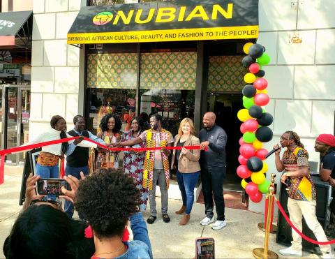 Nubian ribbon cutting ceremony in front of new storefront